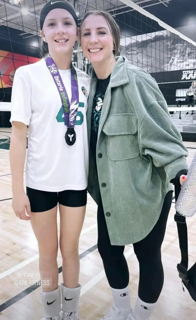 Finleigh Kane wearing an Ontario Volleyball medal beside her coach